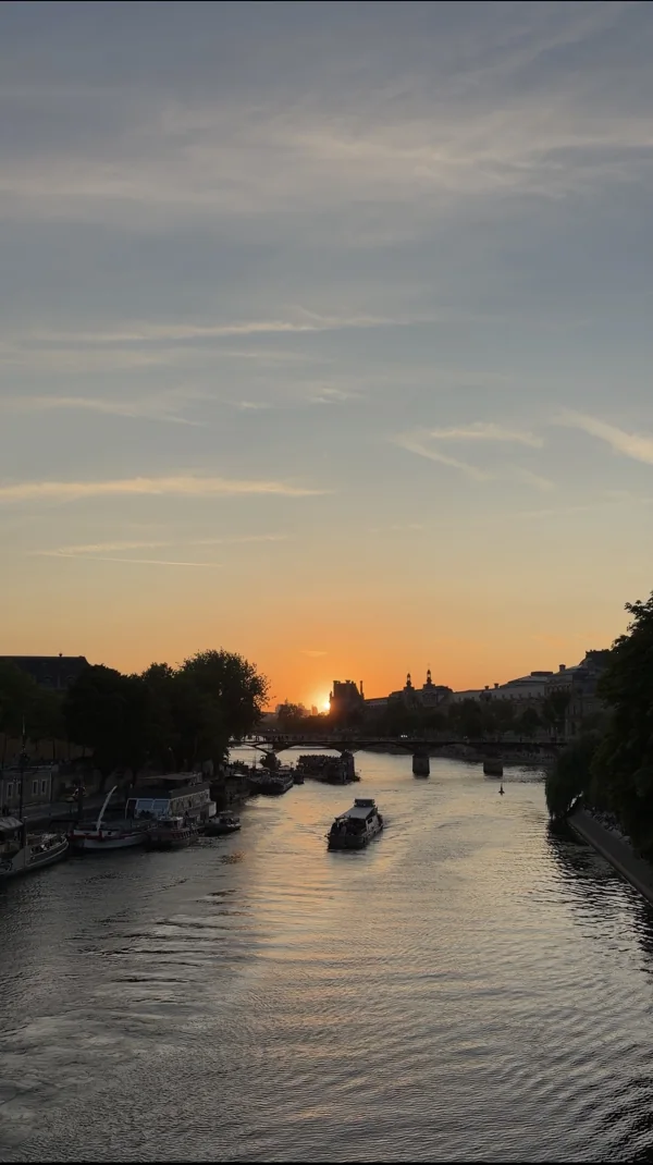 Riverboats and a bridge under a warm sunset
